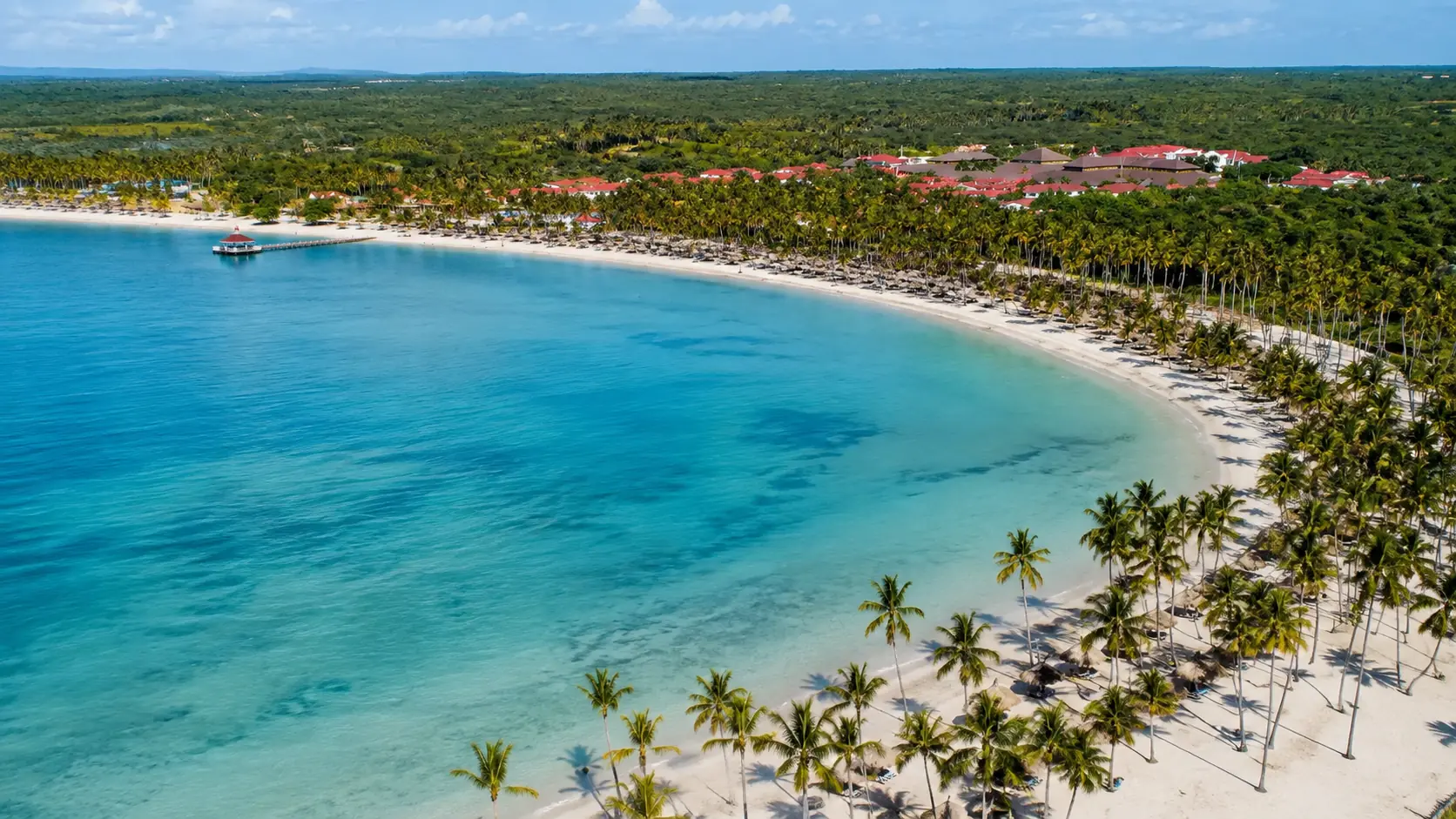 la-romana-playa-nueva-romana-hero-v2 Aerial view of Playa Nueva Romana’s palm-lined Caribbean bay