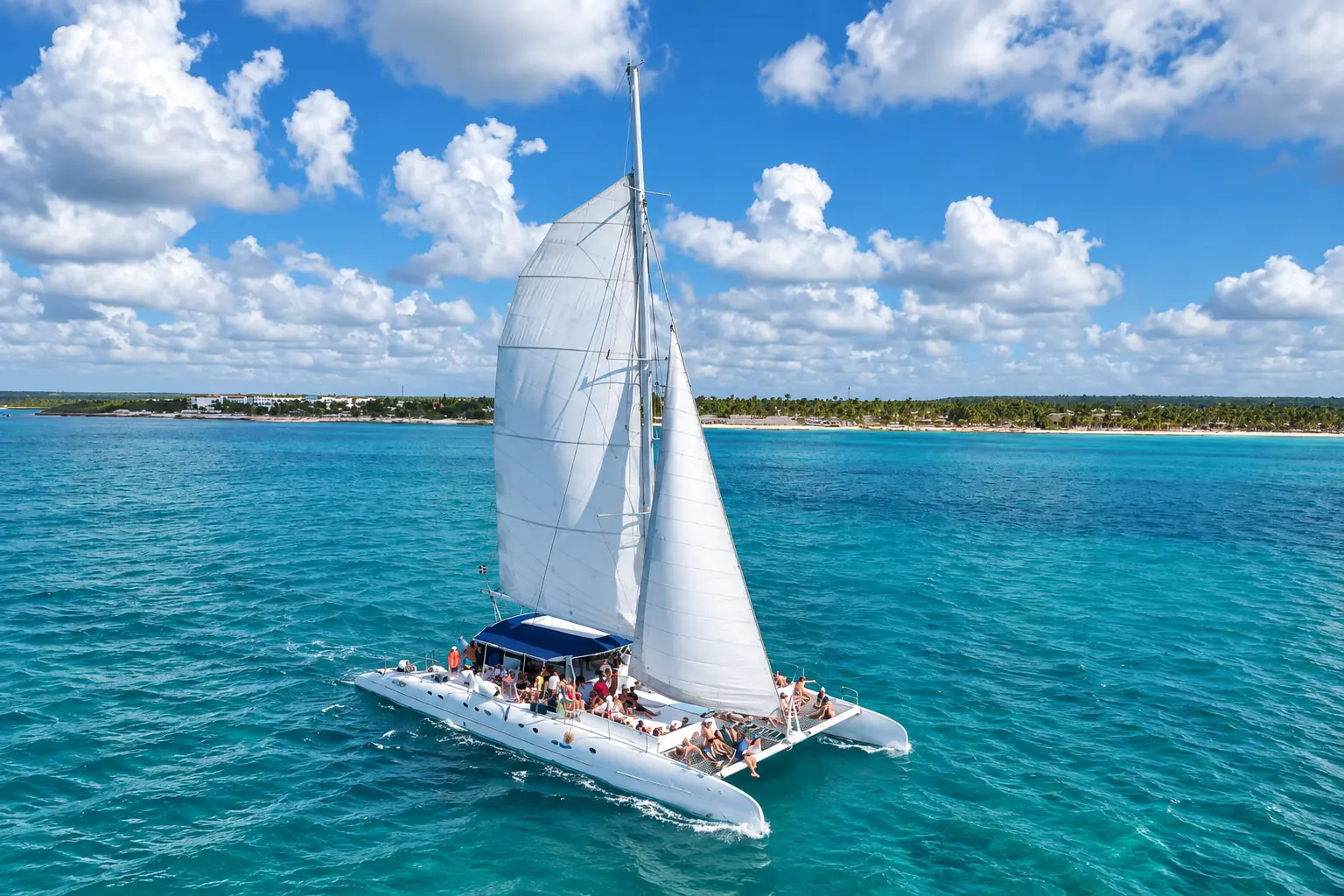 Guests aboard a white catamaran sailboat under full sail during an Isla Saona excursion.